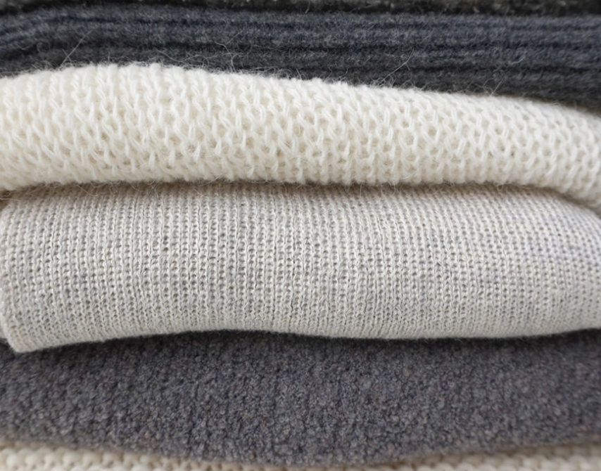 Stapel nachhaltiger Strickmode in verschiedenen Grautoenen