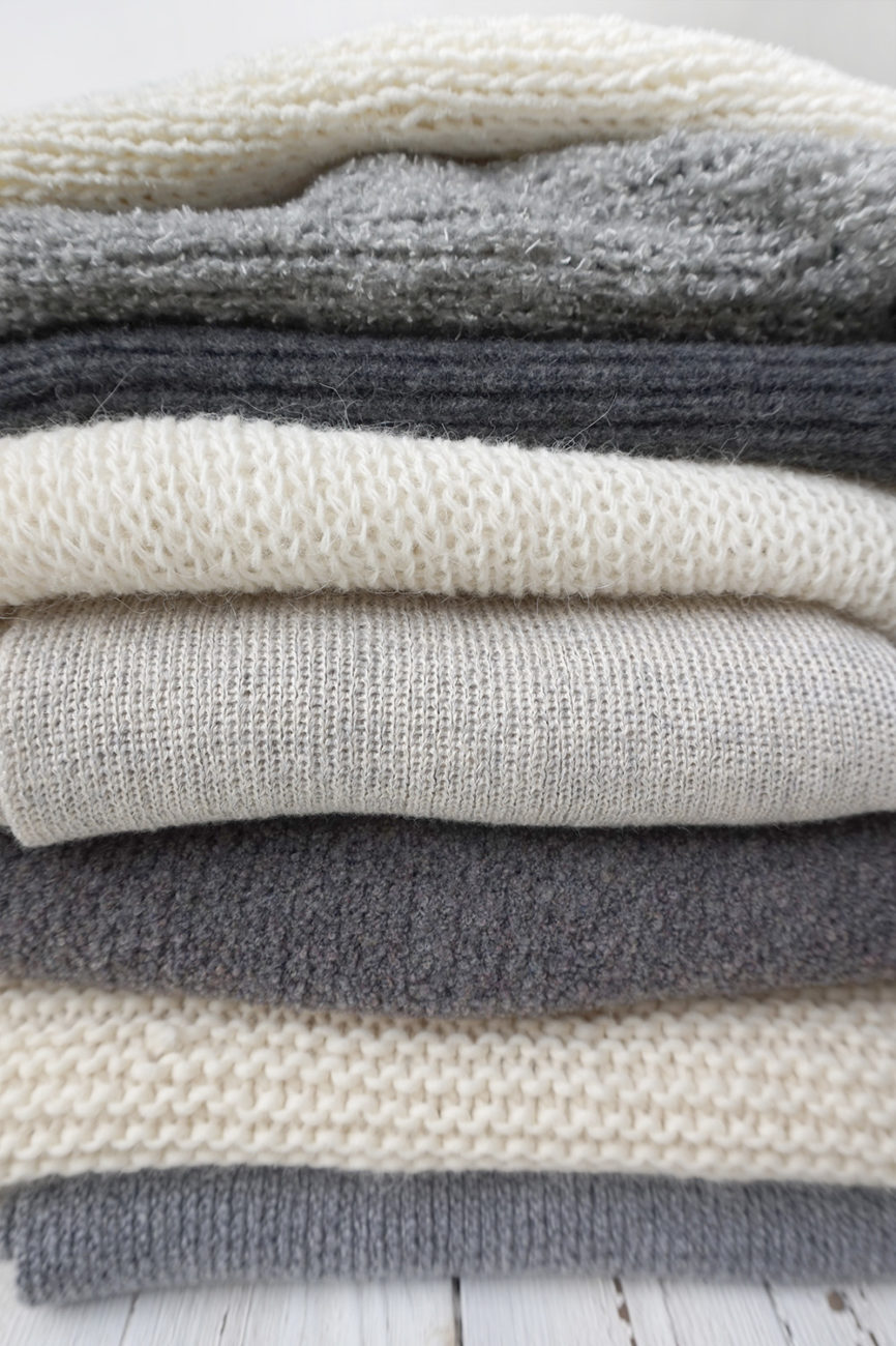 Stapel nachhaltiger Strickmode in verschiedenen Grautoenen